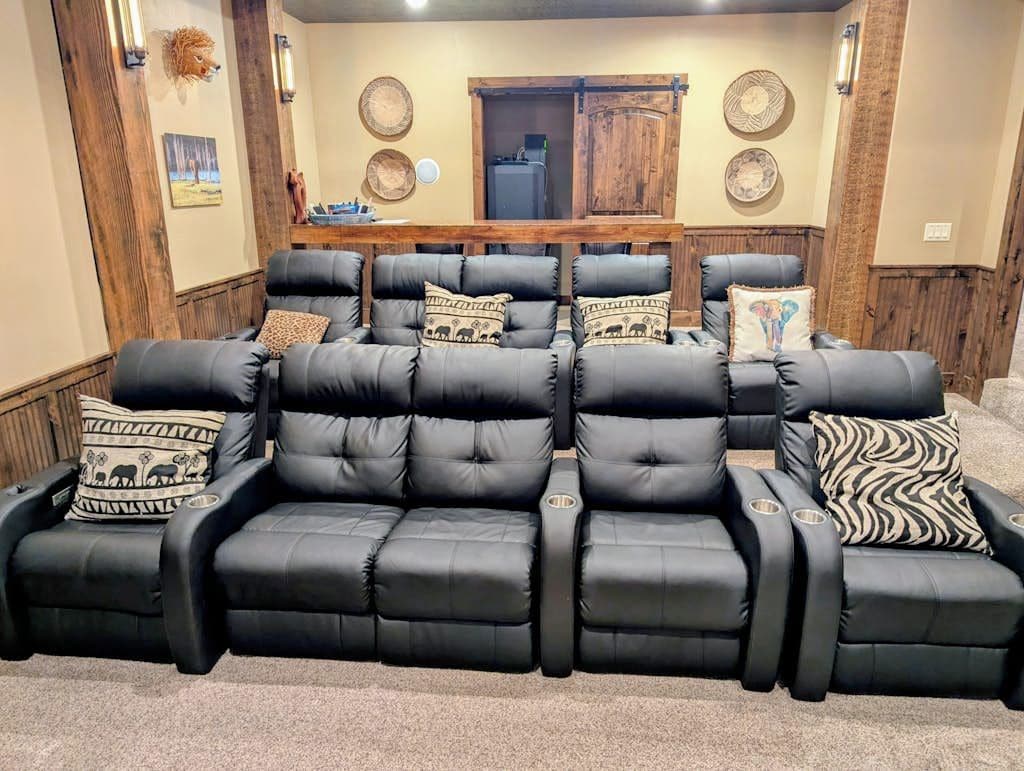 A black leather sofa with multiple cushions, a wooden door, and decorative wall plates.