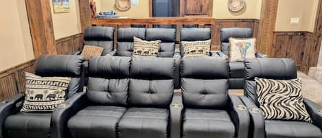 A black leather sofa with multiple cushions, a wooden door, and decorative wall plates.
