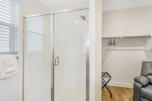 Un bany modern amb una cabina de dutxa de vidre, una barra de tovalloles i una zona de seients amb una cadira.