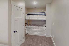 Ein Zimmer mit einem Etagenbett, einer weißen Tür und Teppichboden.