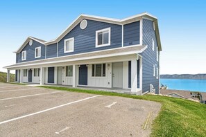 A two-story building with a covered porch and a parking lot in front. - Lakeview Condo 941-1 (Garden City)
