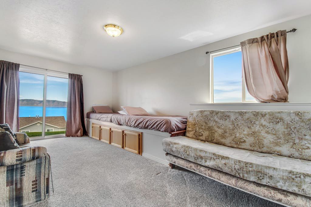 Une chambre à coucher avec un lit, un canapé, une fenêtre avec des rideaux et une vue sur une maison.