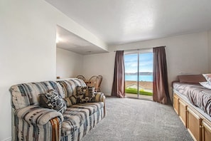 A room with a sofa, a bed, a dining table with chairs, and a view of the outdoors. - Lakeview Condo 941-1 (Garden City)