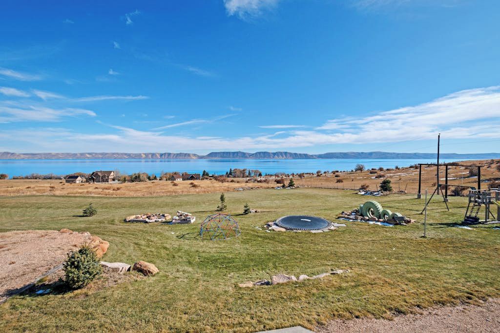 A rural landscape with a clear sky, a body of water, and a distant mountain range.