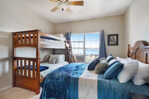 A bedroom with bunk beds, a ceiling fan, a large window with curtains, and a framed picture on the wall. - The Lakehouse - Lake Views, Sleeps 31, Dogs OK (Garden City)