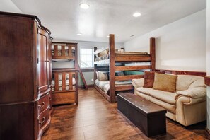A room with a bunk bed, a wooden wardrobe, a leather sofa, and a wooden bench. - The Lakehouse - Lake Views, Sleeps 31, Dogs OK (Garden City)
