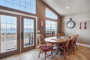 A dining area with a large table and chairs, a clock on the wall, and a sign that says 'Friends & Family Gather Here.' - The Lakehouse - Lake Views, Sleeps 31, Dogs OK (Garden City)