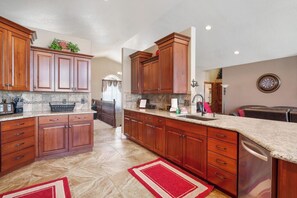 Cocina con armarios de madera, encimeras de granito y alfombra roja.