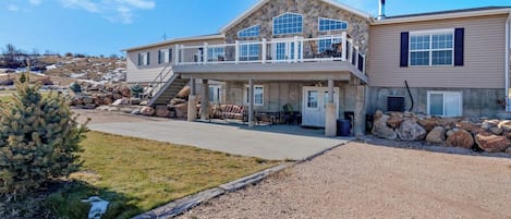 A two-story house with a balcony, a stone facade, and a gravel driveway.