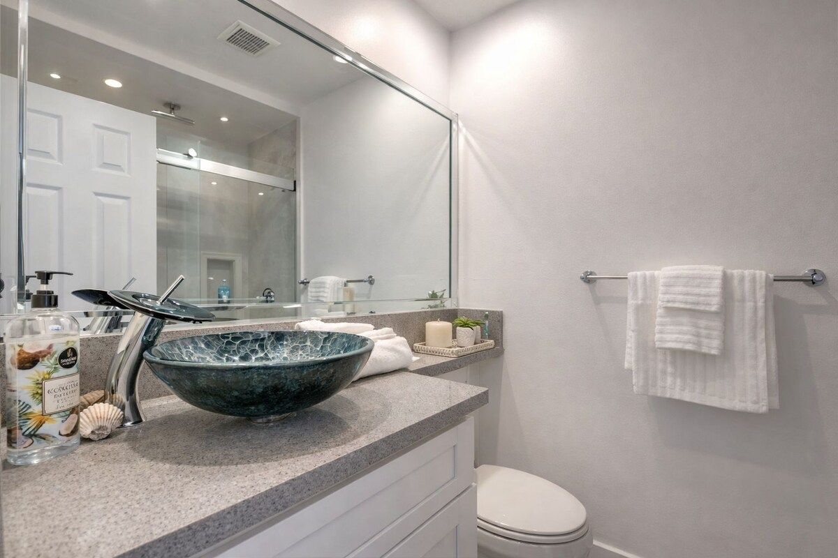 A modern bathroom with a large glass bowl sink, a toilet, and a towel rack.