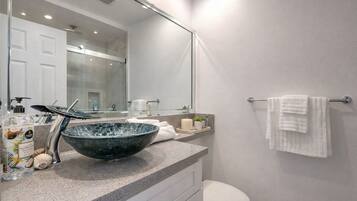 Une salle de bain moderne avec un grand lavabo en forme de bol en verre, des toilettes et un porte-serviettes.