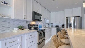 Una cocina moderna con armarios blancos, electrodomésticos de acero inoxidable y una encimera amplia.