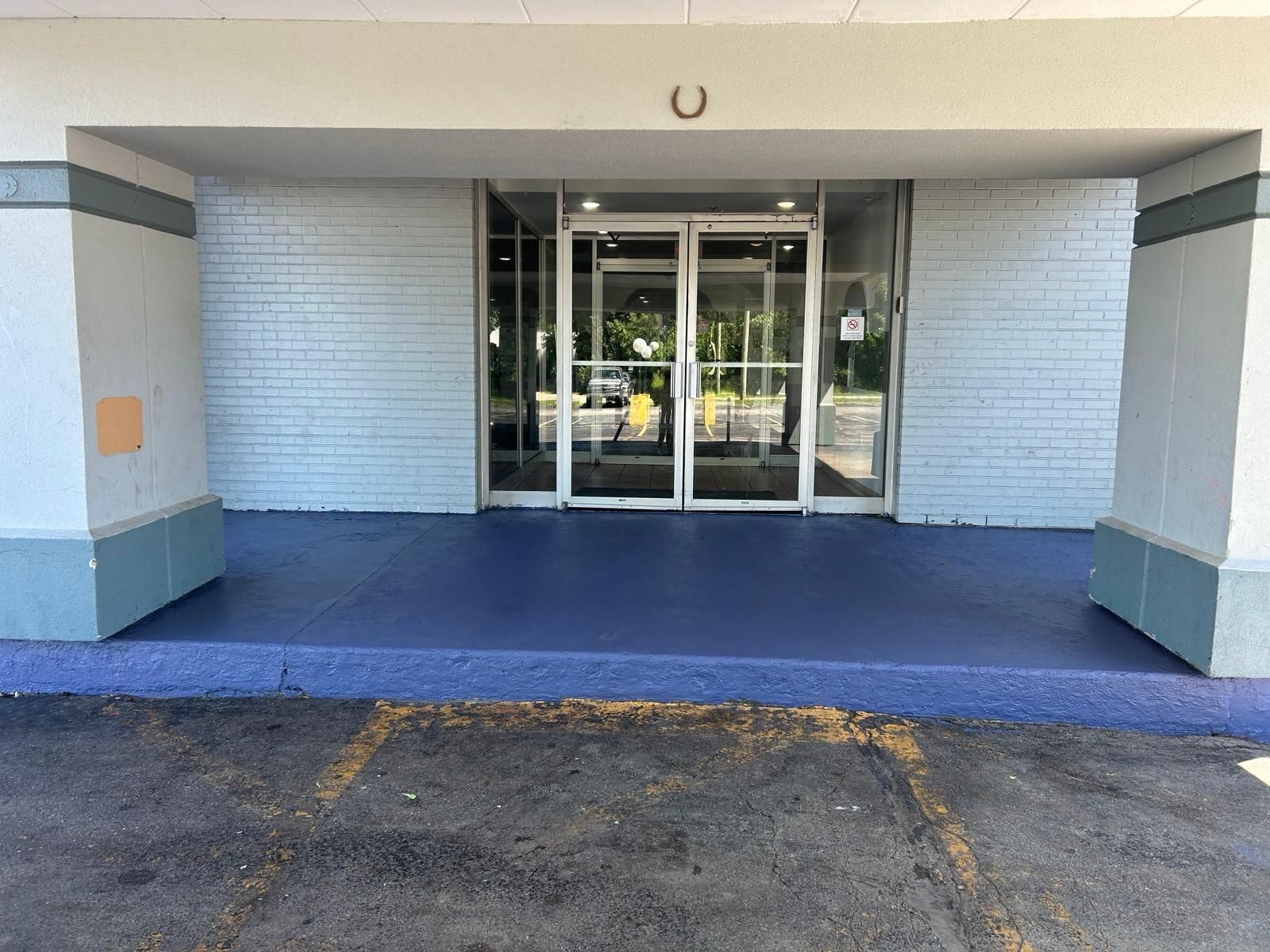 A building entrance with a glass door and a blue-painted ground.