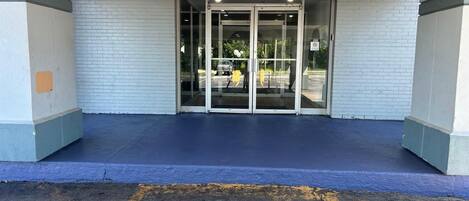 Entrada de un edificio con puerta de vidrio y suelo pintado de azul.