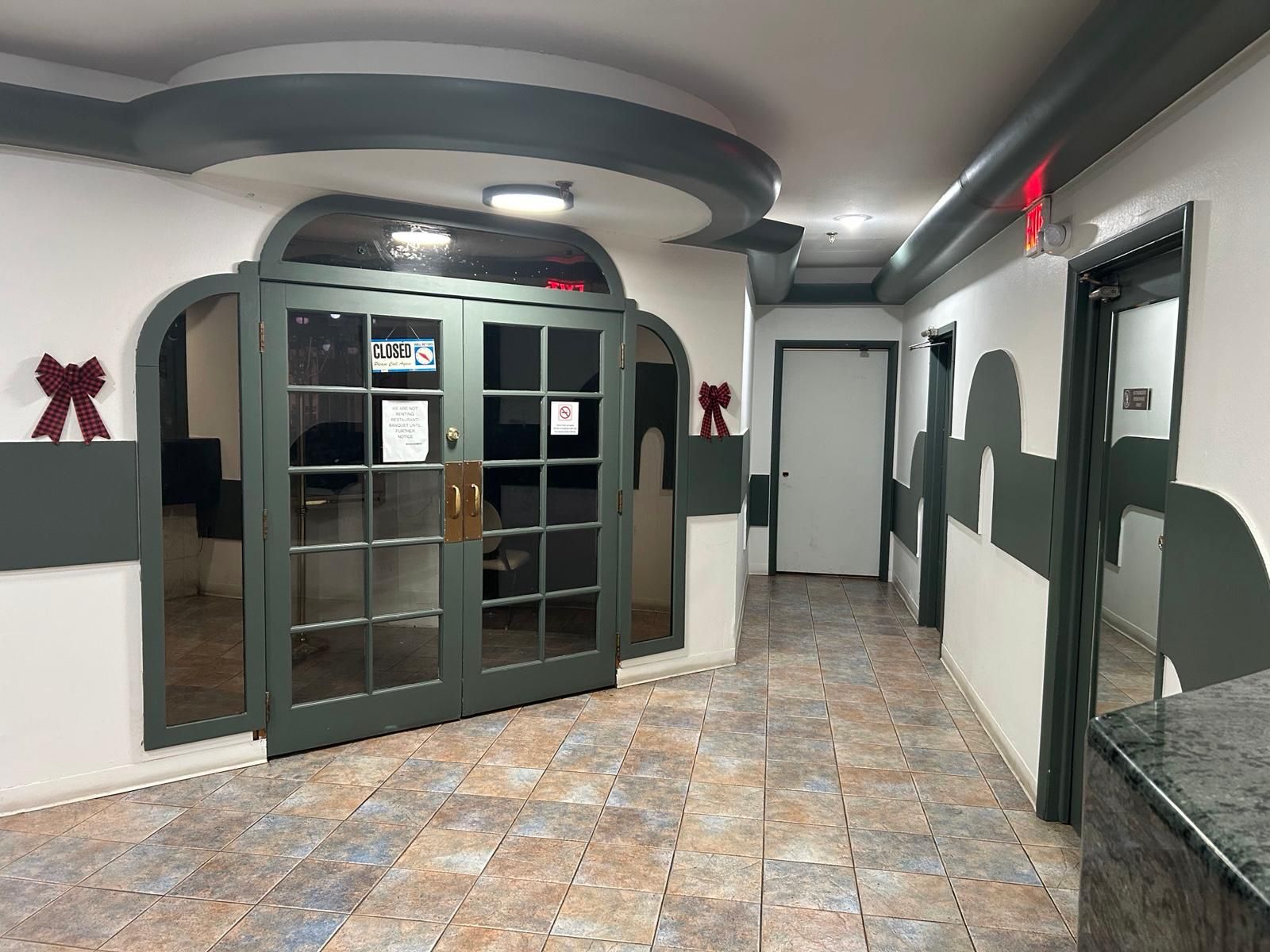 A hallway with a green door, a closed sign, and a tiled floor.