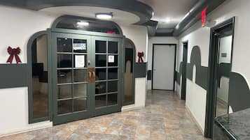 A hallway with a green door, a closed sign, and a tiled floor.