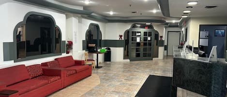 Un hall d’entrée avec un canapé rouge, un comptoir d’accueil et une porte verte.