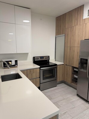 Una cocina moderna con armarios blancos, estufa de acero inoxidable y horno empotrado.
