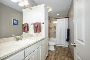 Un bagno con doppio lavabo, un water, una doccia con tenda e uno specchio grande.
