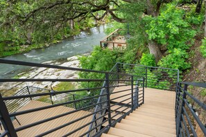 A wooden staircase leading to a viewing platform overlooking a river, surrounded by lush greenery. - Guadalupe Horseshoe Hideaway CL 320 (Canyon Lake)