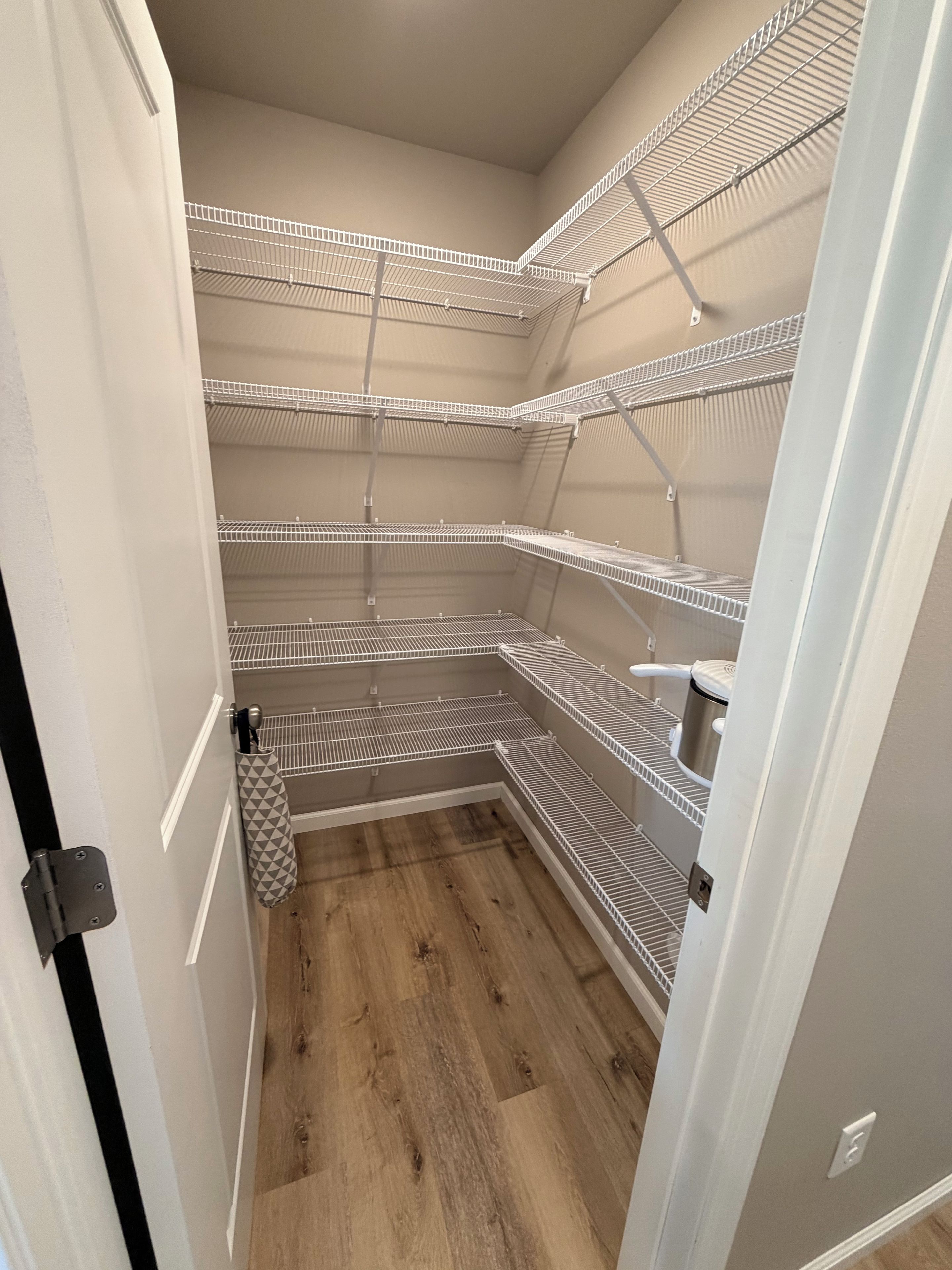 A small, enclosed storage area with metal shelving units and a wooden floor.