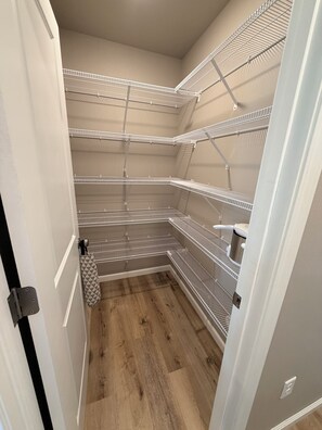 Un petit espace de rangement fermé, doté d’étagères métalliques et d’un plancher en bois.