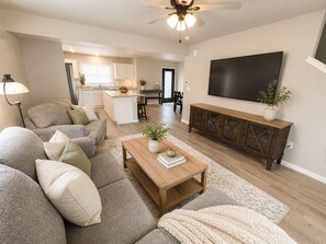 A modern living room with a sofa, coffee table, and TV. - 3-bedroom townhome -8 Miles From Downtown Iowa City (Hills)