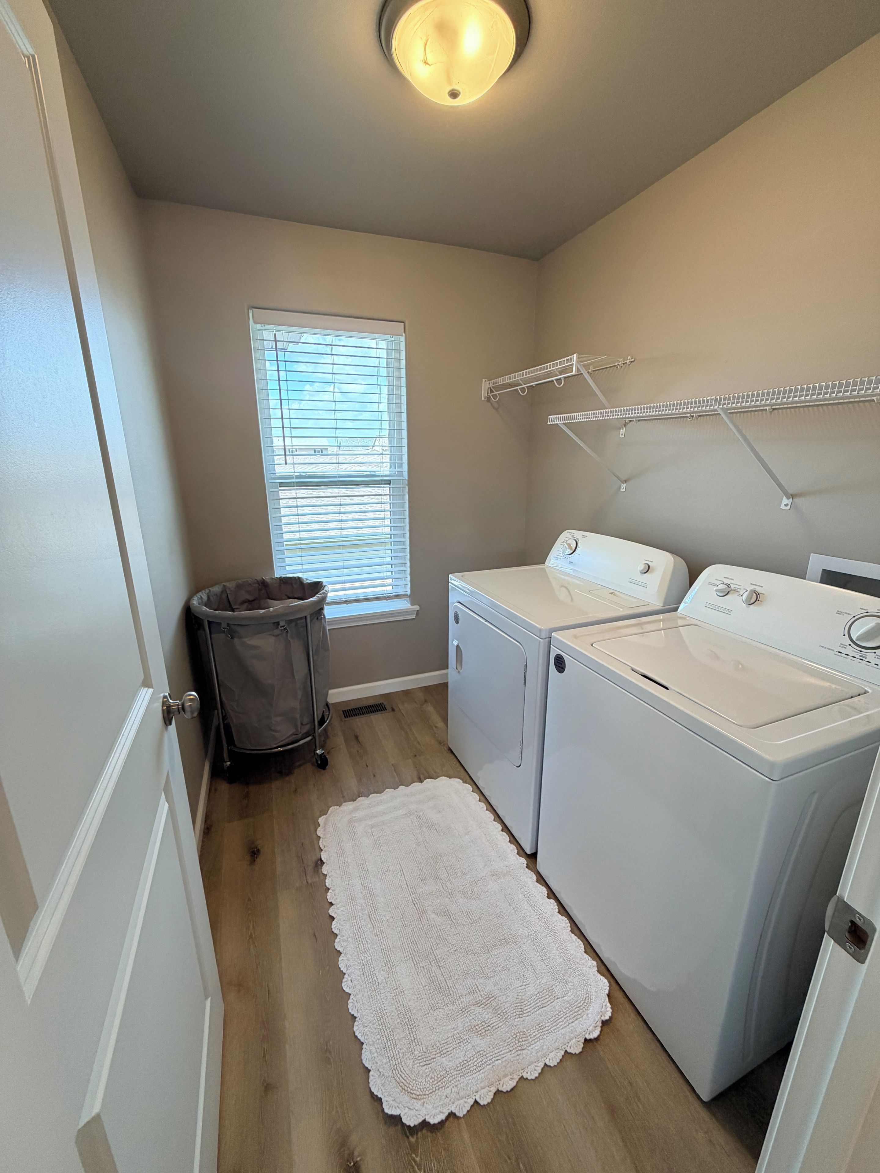 A laundry room with a washing machine, dryer, and a drying rack.