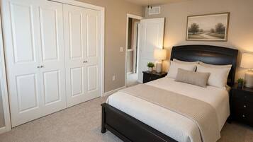 A bedroom with a bed, bedside tables, a ceiling fan, a door, and a framed picture on the wall.