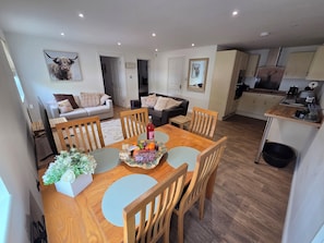 A dining area with a wooden table, chairs, and a fruit platter. - Luxury 2-Bed New Forest Retreat with Paddocks, Animals (Dogs Welcome) (Southampton)
