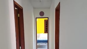 A narrow hallway with white tiled flooring and wooden doors on either side.