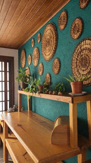 Una habitación con un banco de madera, una pared texturizada color aguamarina y adornos colgantes tejidos.