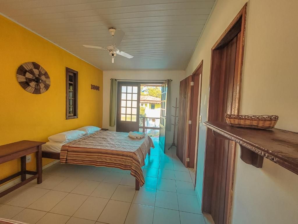 Ein Zimmer mit einem Bett, einem Deckenventilator, einem Fenster und einer Tür.