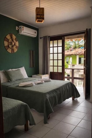 A hotel room with two beds, a large window, and a view of the outside.