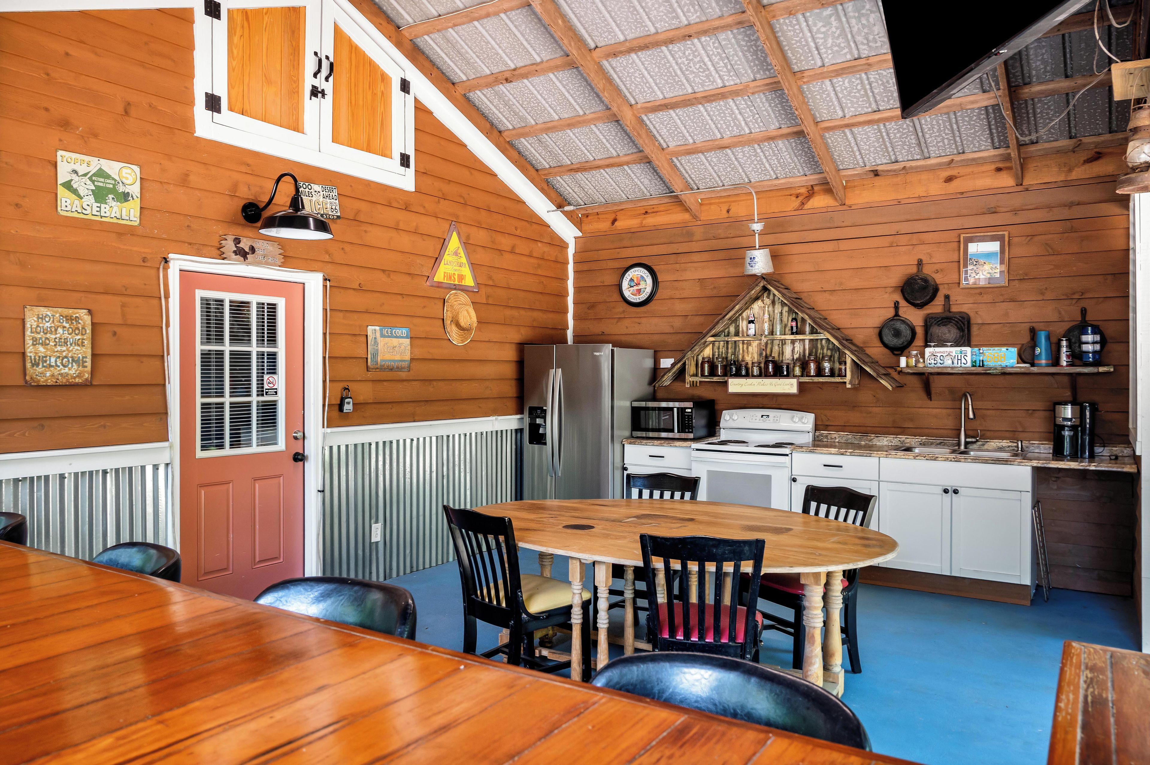 A wooden interior with a dining area, kitchen, and a clock on the wall.