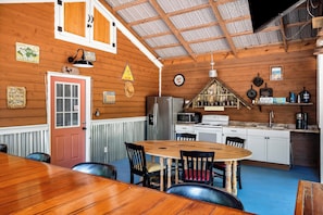 A wooden interior with a dining area, kitchen, and a clock on the wall. - Quiet and cozy Coastal Cottage (Charleston)