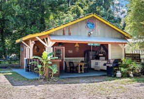 A rustic building with a corrugated metal roof, a wooden porch, and a sign indicating 'Meeting Street.'