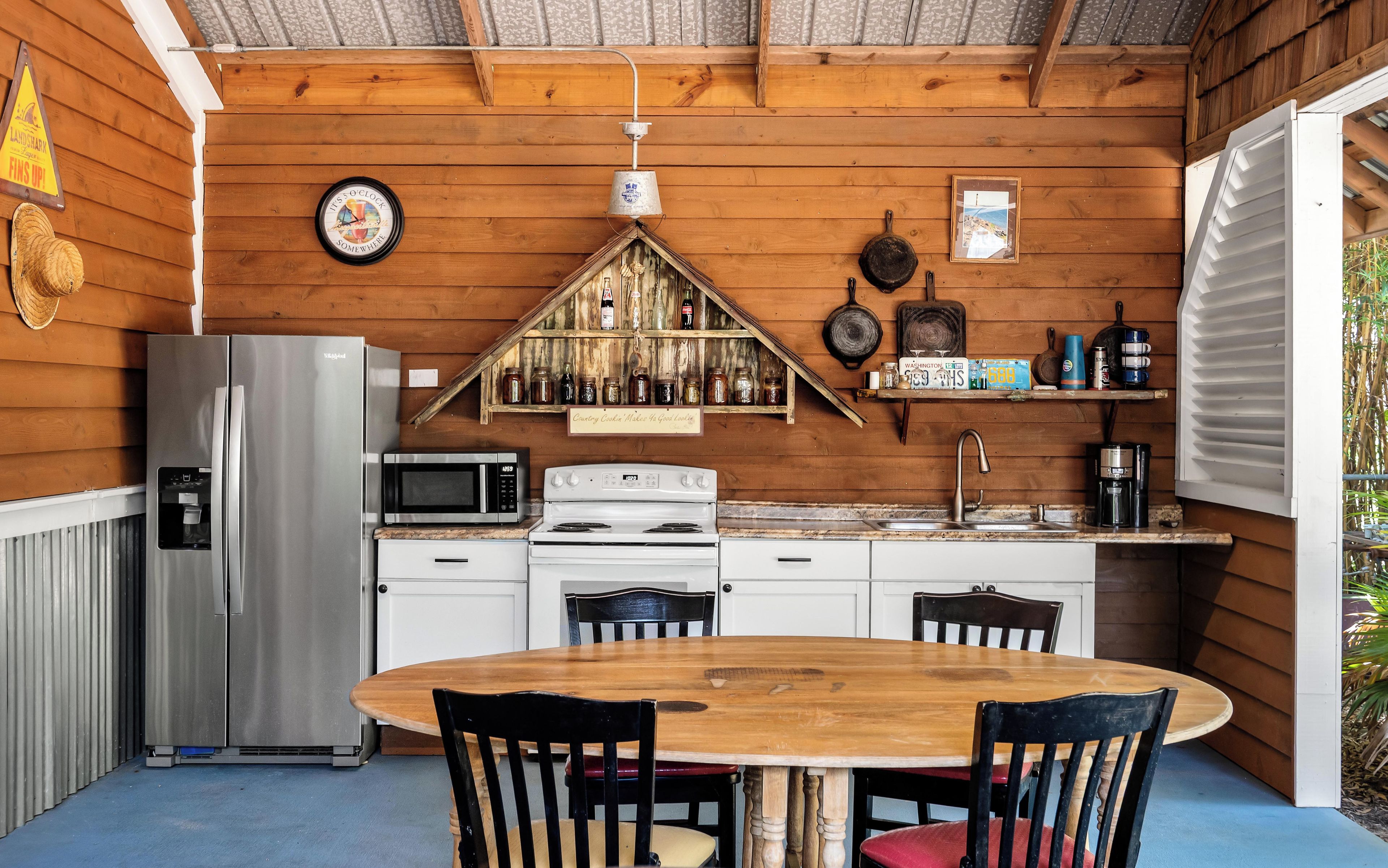 L’intérieur d’un chalet en bois comprend un coin cuisine équipé d’un réfrigérateur, d’un four à micro-ondes, d’une cuisinière et d’une table à manger avec des chaises.