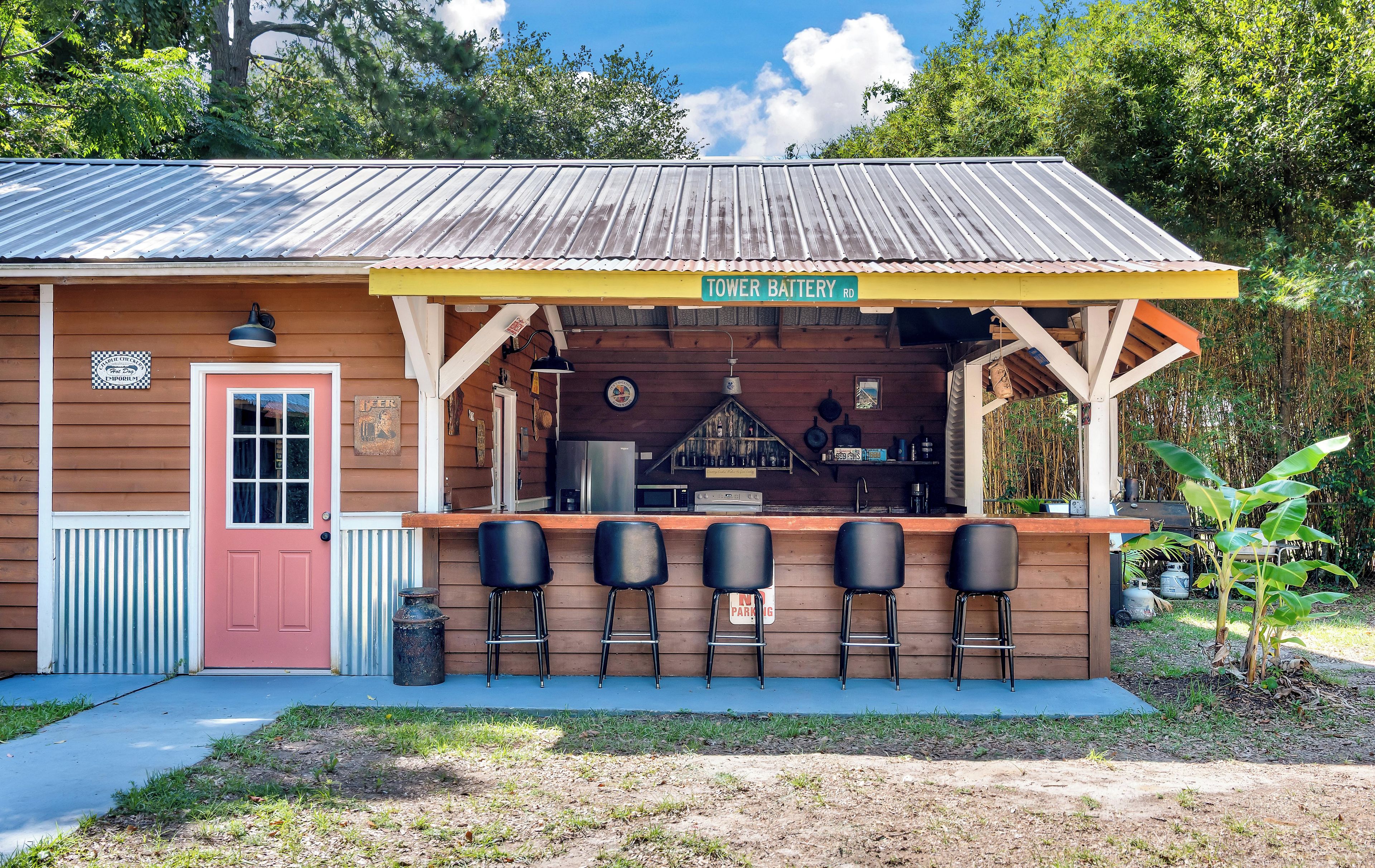 Un pequeño edificio con un toldo amarillo que dice 'TOWER BATTERY RD' y una zona de bar con taburetes.