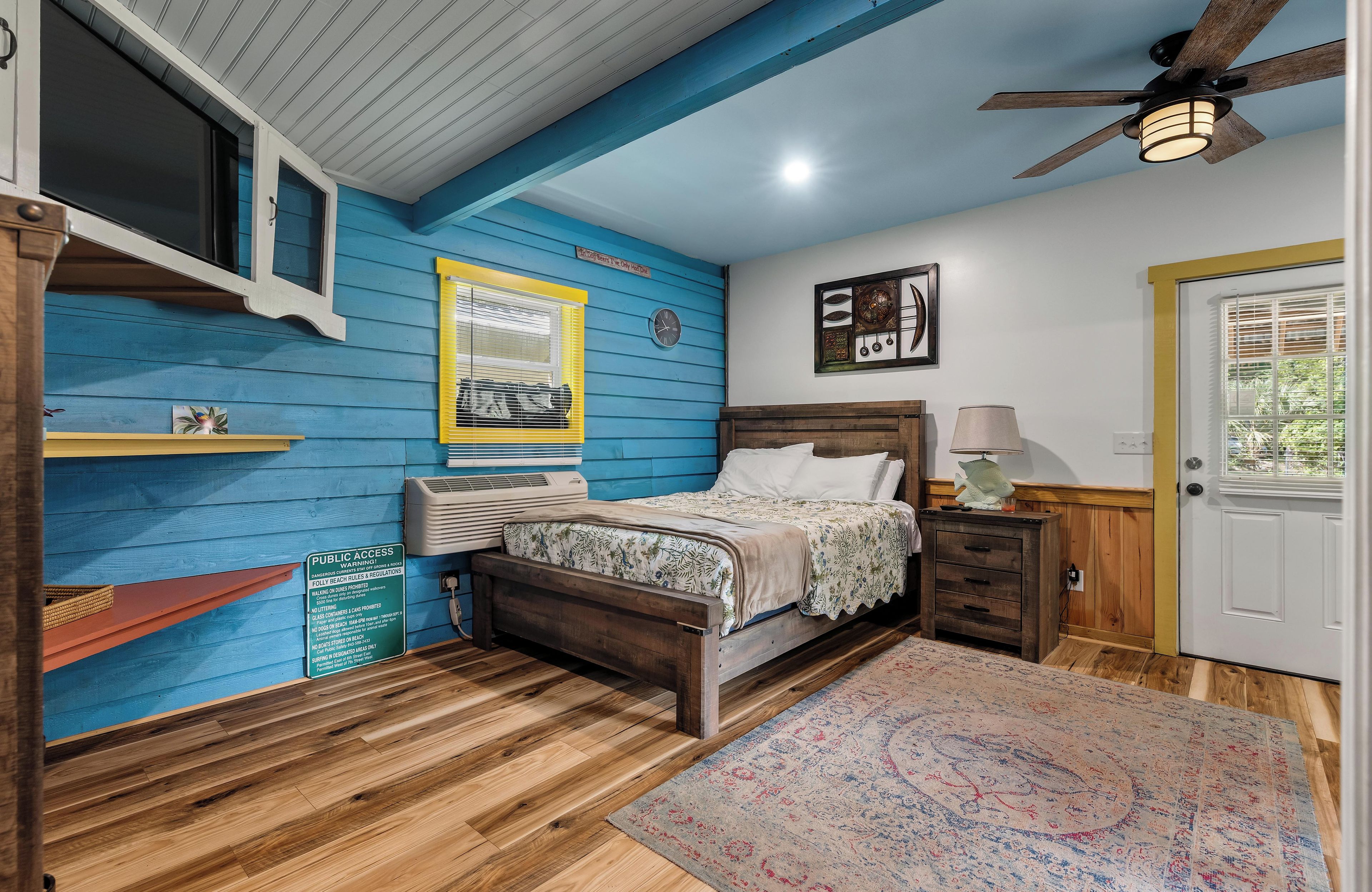 Un dormitorio con una cama de madera, una mesita de noche, una lámpara, un reloj y una ventana con persianas.