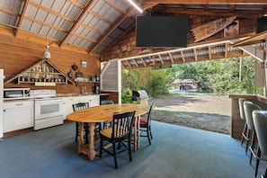 A rustic kitchen with a wooden table and chairs, a large window, and a view of the outdoors. - Quiet and cozy Coastal Cottage (Charleston)