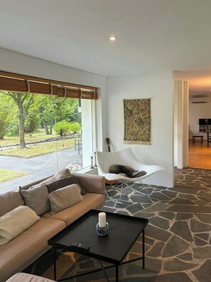 A modern living room with a sofa, a coffee table, and a view of a garden. - Private summer house in nature near Ebeltoft (Ebeltoft)
