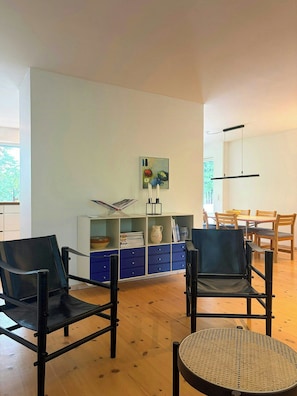 A modern living room with two black leather chairs, a round woven table, and a bookshelf with various items. - Private summer house in nature near Ebeltoft (Ebeltoft)
