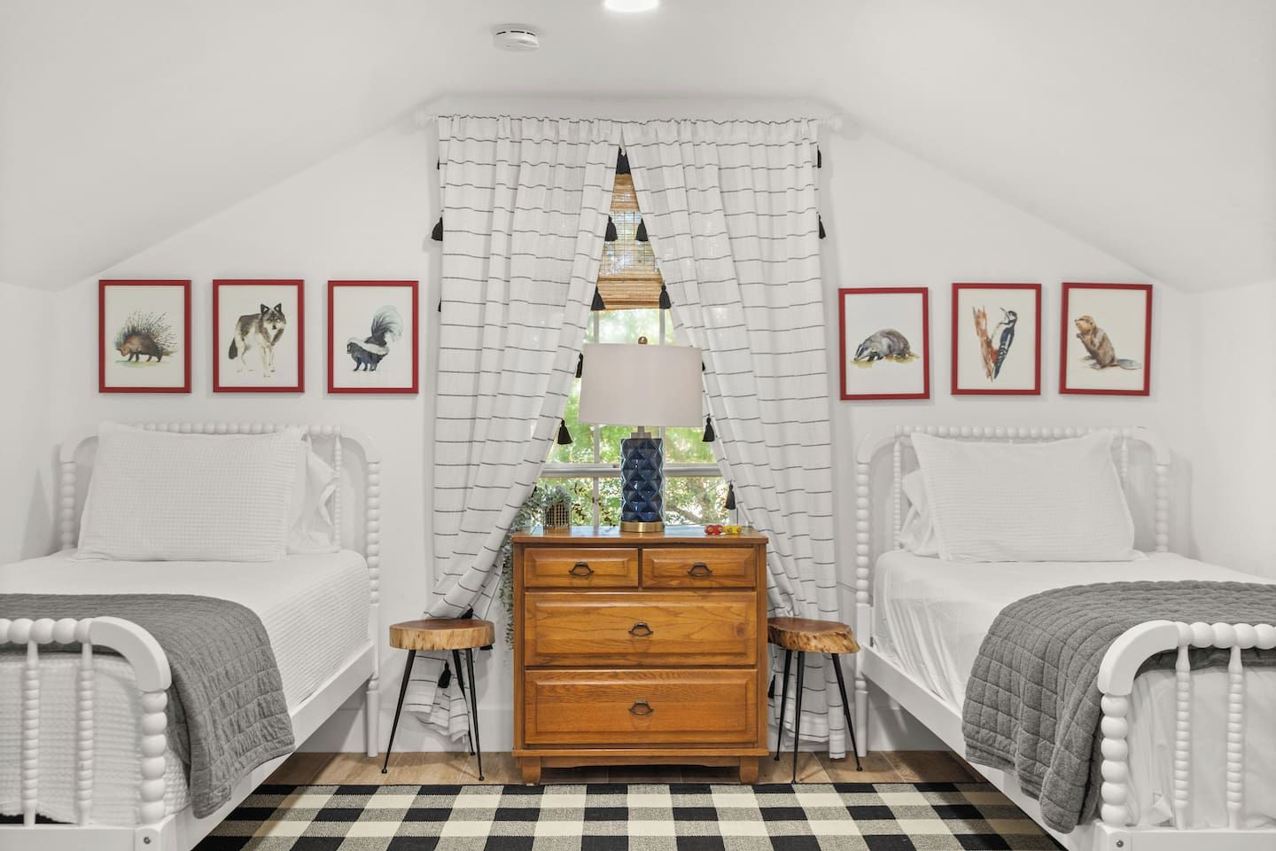 A bedroom with two beds, a dresser, and a window with curtains.