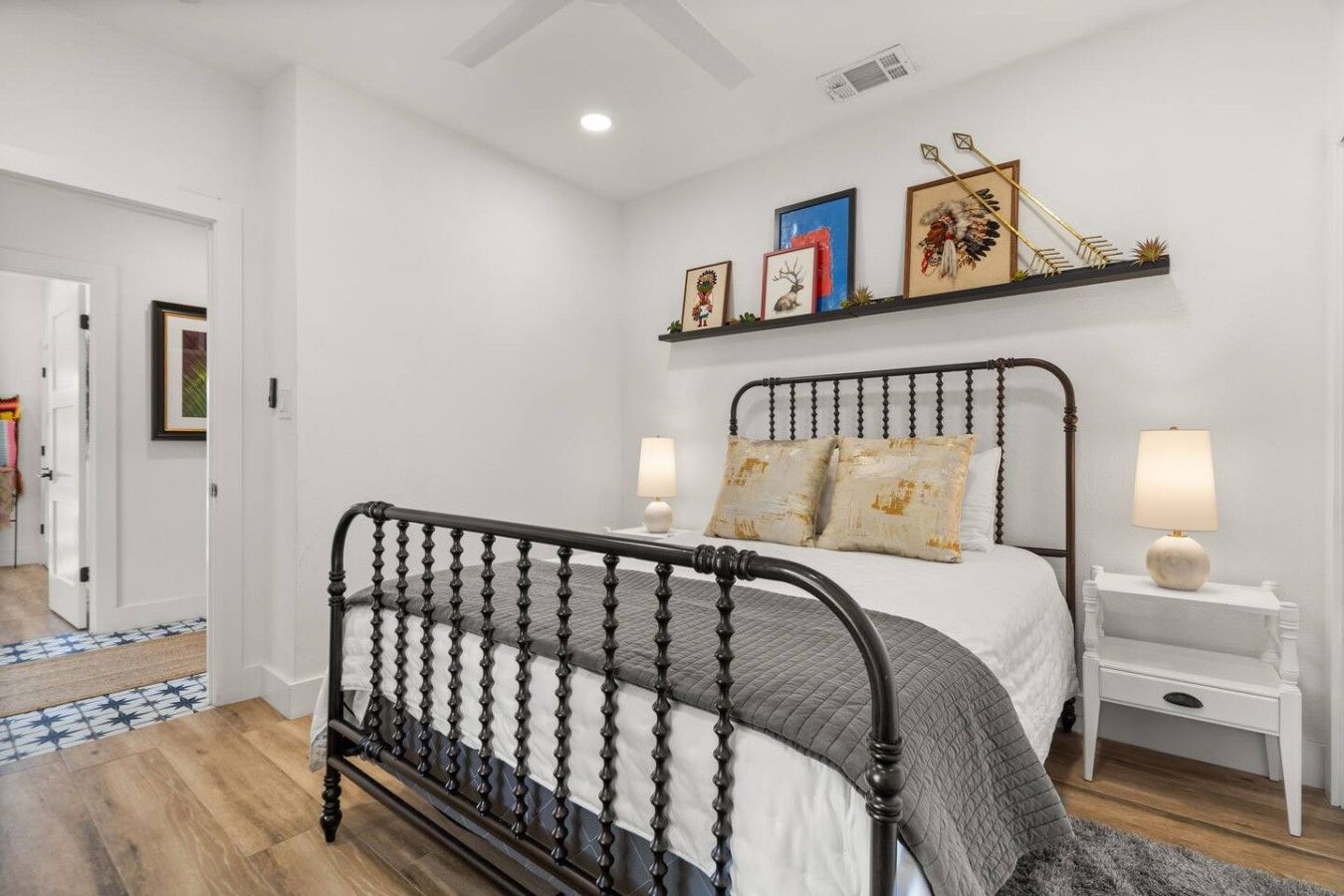 A bedroom with a bed, bedside tables, a headboard, and wall-mounted artwork.