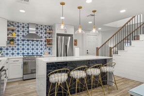 A modern kitchen with a central island, stainless steel appliances, and a staircase leading to an upper level. - Modern Home Near Downtown Georgetown (Georgetown)
