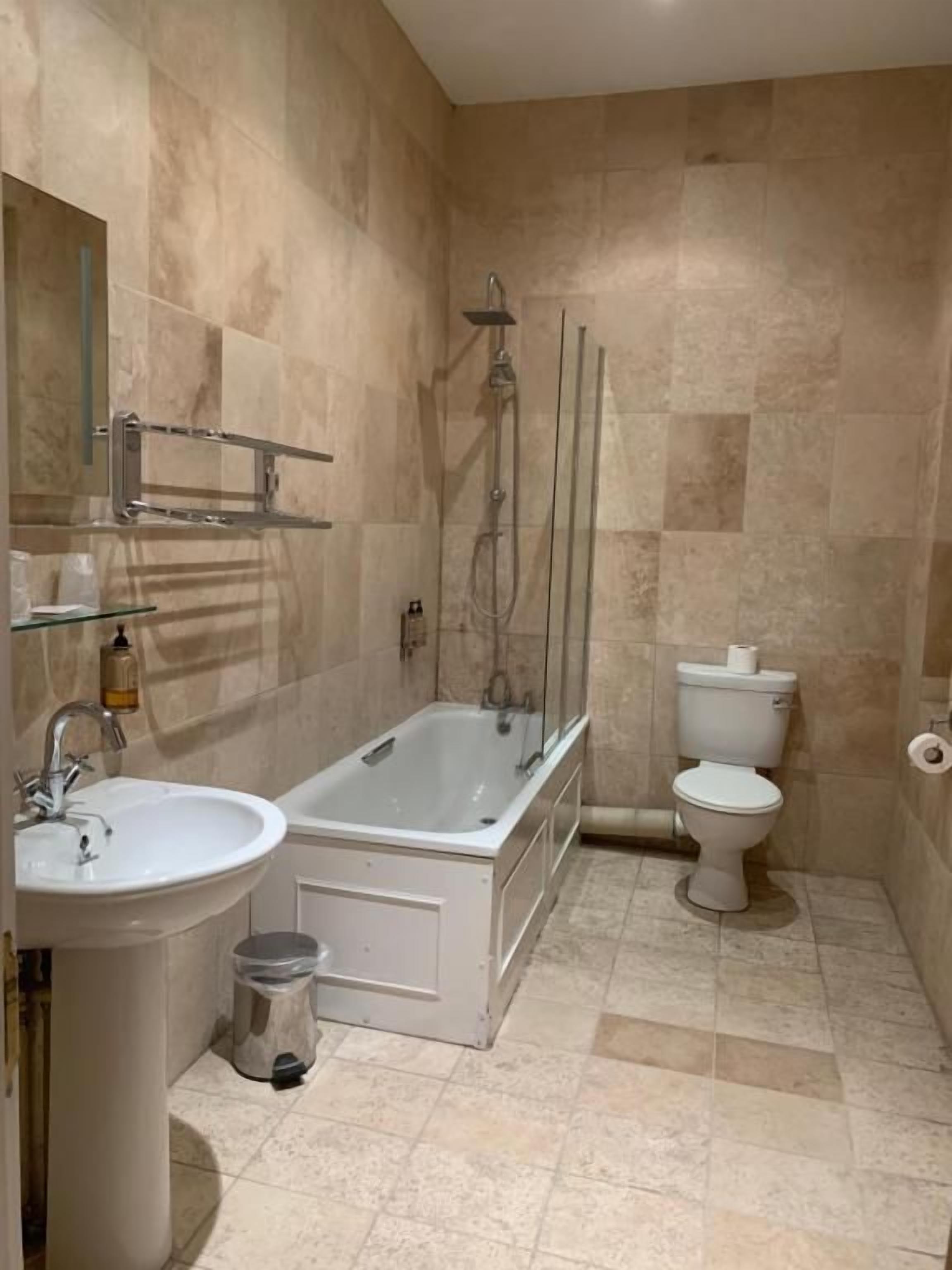 A bathroom with a bathtub, toilet, sink, and a mirror.
