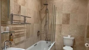 A bathroom with a bathtub, toilet, sink, and a mirror. - Waterloo Hotel (Newport)