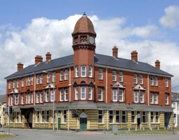 A red-brick building with a central tower and a clock. It has multiple windows and a sign that reads 'Waterloo Hotel.'