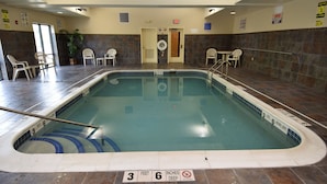 Una piscina interior con suelo de baldosas, indicadores de profundidad marcados y un cartel de prohibido bucear.